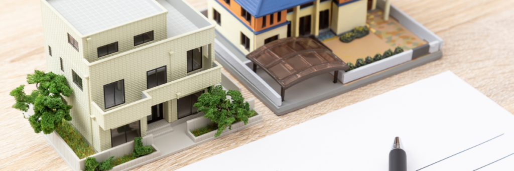 A real estate investors desk with models of houses on it and a pen